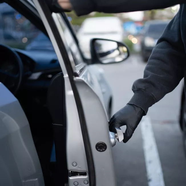 Close-up shot of a thief wearing a black shirt and black gloves.
